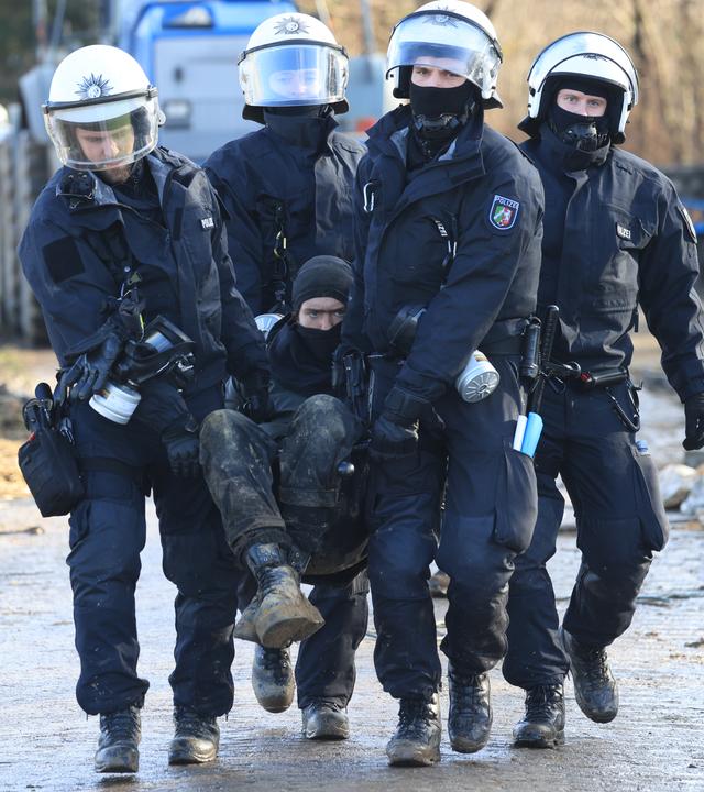 Vier Polizisten tragen einen Klimaaktivisten weg