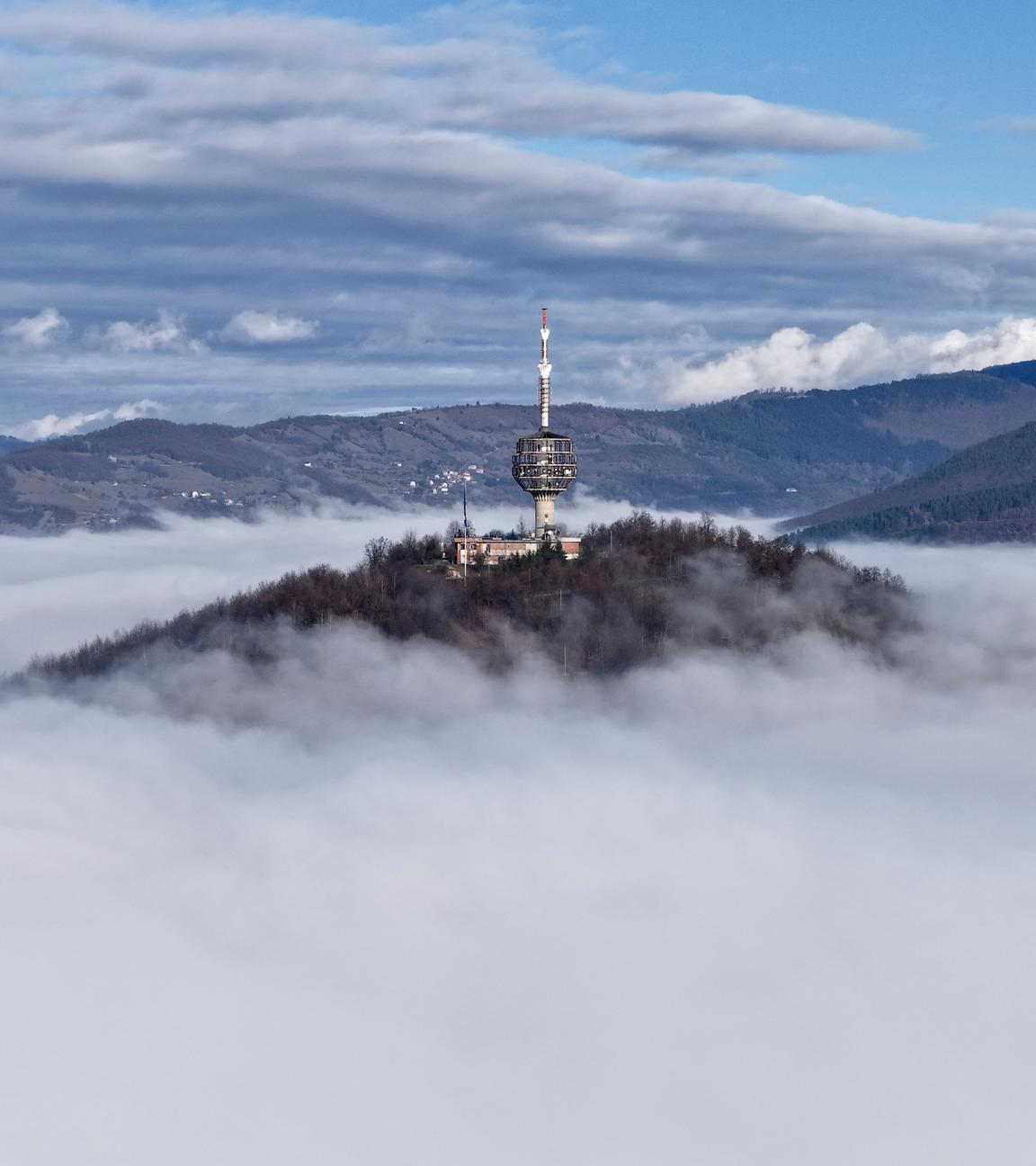 ARCHIV - 22.01.2025, Bosnien-Herzegowina, Sarajevo: Die Luftaufnahme des Fernsehturms in Sarajevo zeigt eine dichte Schicht von Nebel und Smog, durch die der Turm zu erkennen ist.