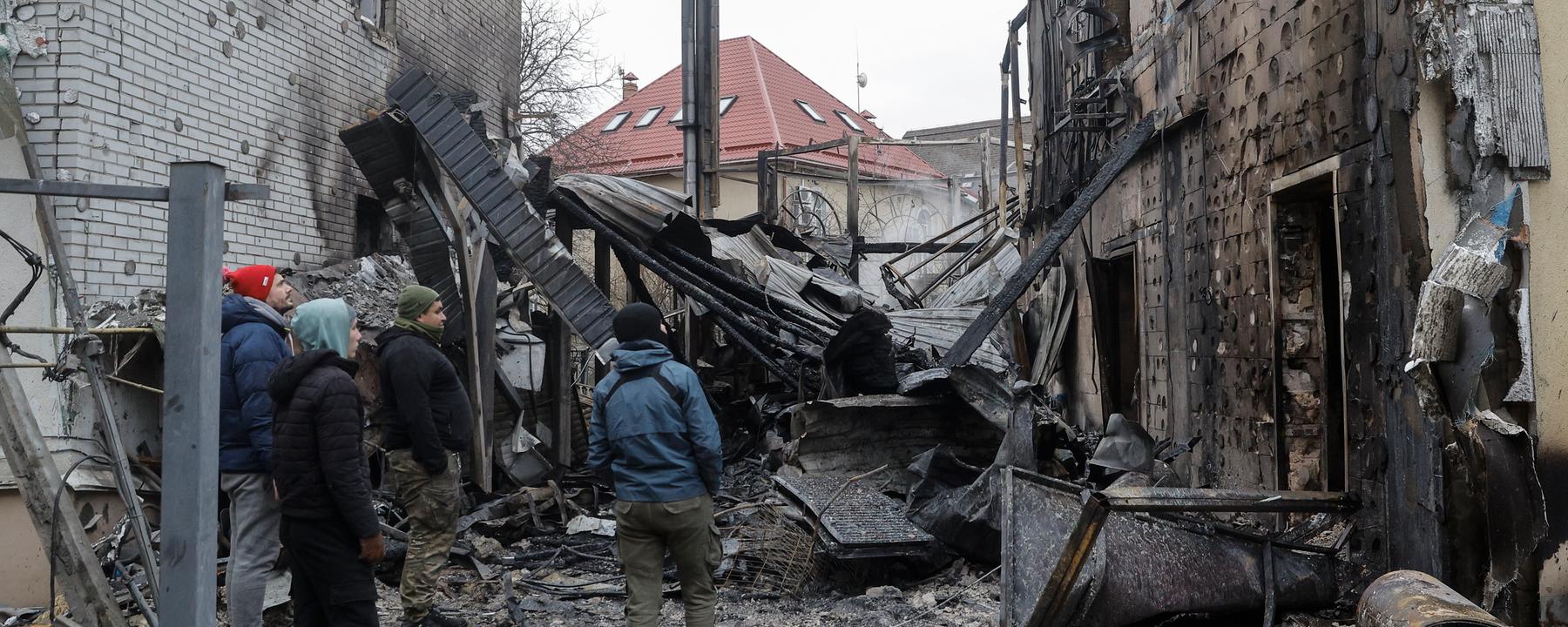 Beschädigtes Wohngebäude in Kiew nach russischem Angriff, Anwohner begutachten die Schäden.