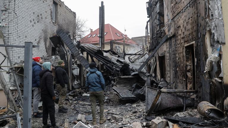 Beschädigtes Wohngebäude in Kiew nach russischem Angriff, Anwohner begutachten die Schäden.