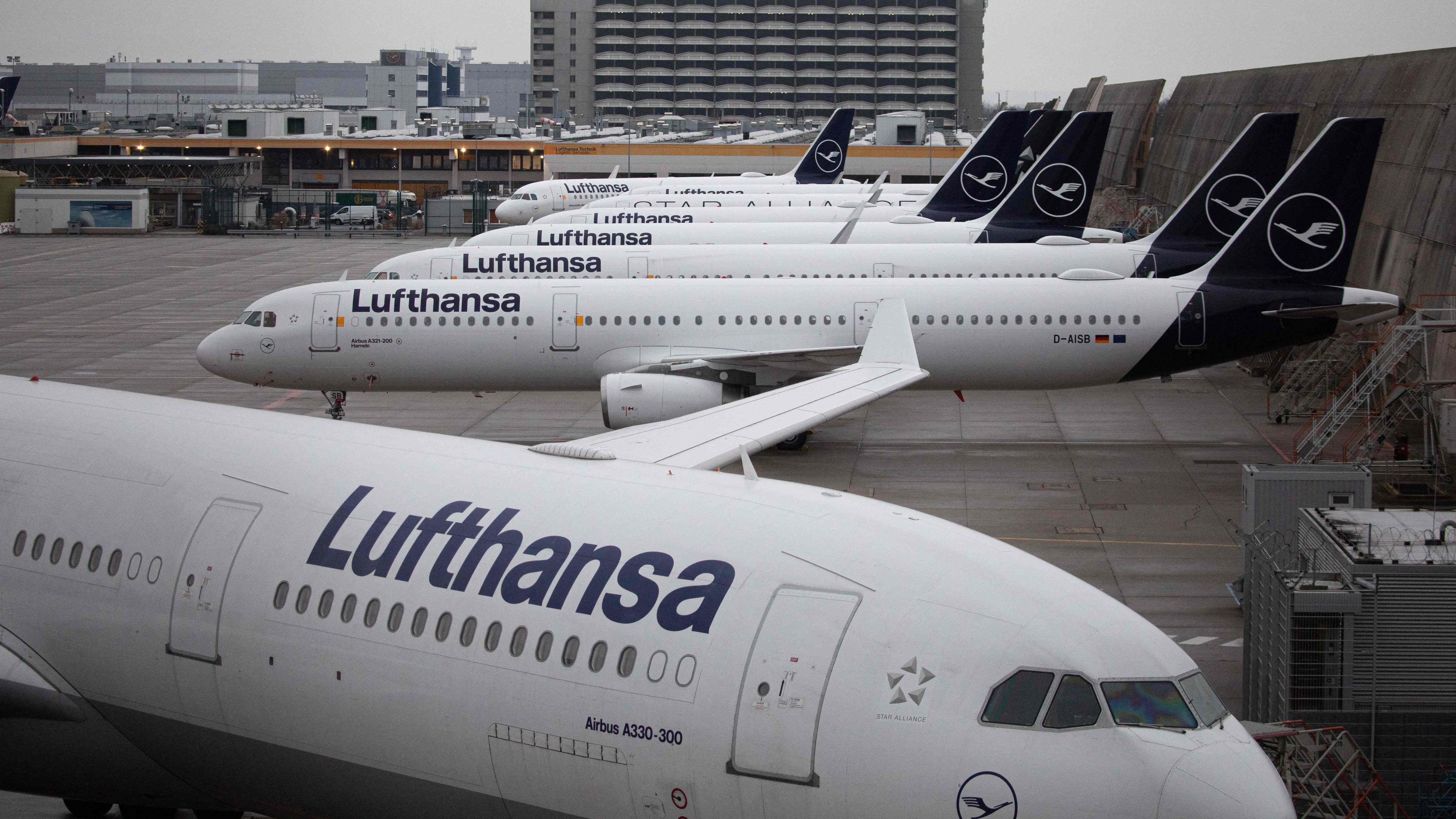 mehrere Lufthansa-Flugzeuge, im Hintergrund ein grauer Himmel 