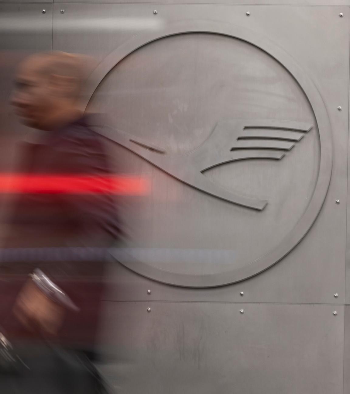 Ein Mann geht vor einem Lufthansa-Logo am Frankfurter Flughafen. 