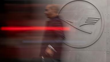 Ein Mann geht vor einem Lufthansa-Logo am Frankfurter Flughafen. 