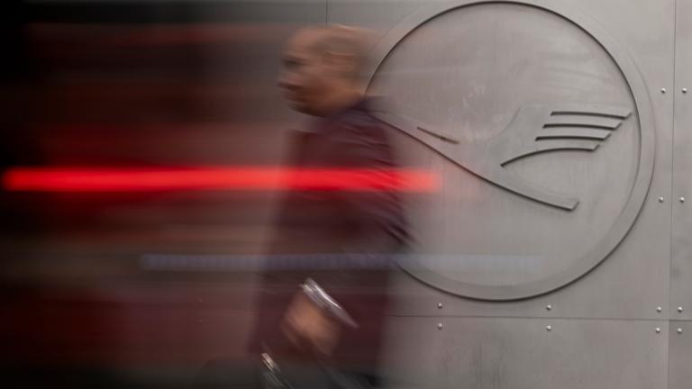 Ein Mann geht vor einem Lufthansa-Logo am Frankfurter Flughafen. 