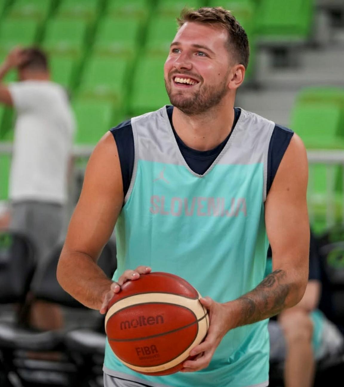 Luka Doncic hält beim Training mit der slowenischen Nationalmannschaft einen Ball in der Hand und lacht