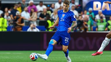 Luka Vušković spielt im blauen Auswärtstrikot Kroatiens den Ball mit seinem rechten Fuß.