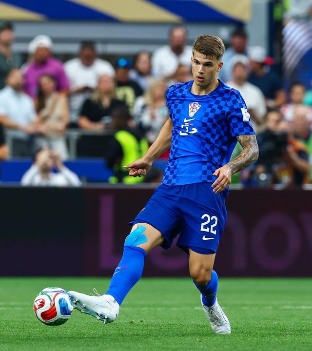 Luka Vušković spielt im blauen Auswärtstrikot Kroatiens den Ball mit seinem rechten Fuß.