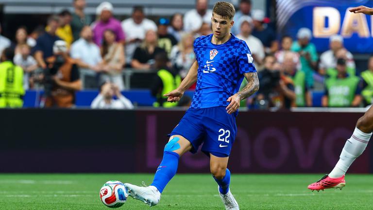 Luka Vušković spielt im blauen Auswärtstrikot Kroatiens den Ball mit seinem rechten Fuß.