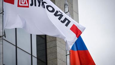Wehende Logobanner des russischen Ölgiganten Lukoil und eine russische Nationalflagge vor dem Lukoil-Hauptgebäude in Moskau.