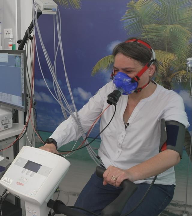 Frau ist beim Arzt auf Spinning Bike und an einem Atemtest-Gerät angeschlossen