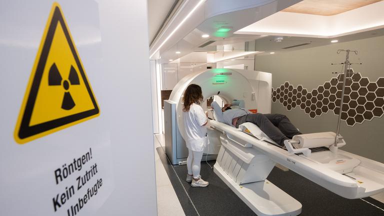 Eine medizinisch-technische Radiologieassistentin, spricht mit einem Mann in einem mobilen Computertomographen CT, bevor er sich einem Lungencheck unterzieht.