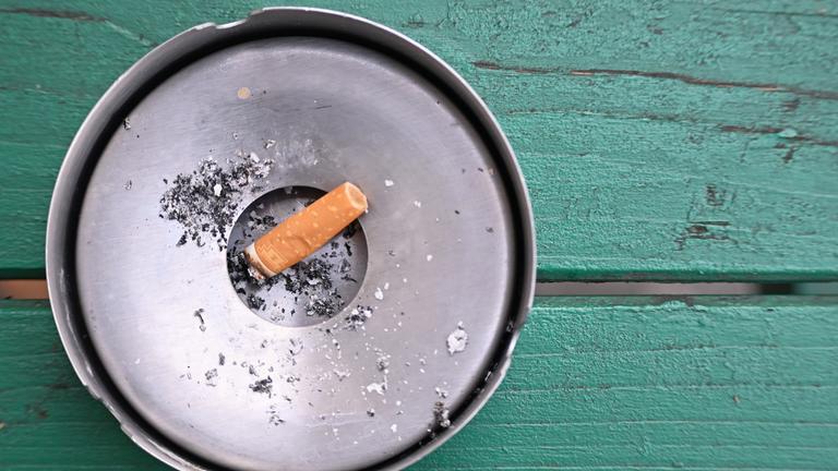 SYMBOLBILD - 27.11.2024, Berlin: Im Freien liegt eine abgebrannte Zigarette in einem Aschenbecher.