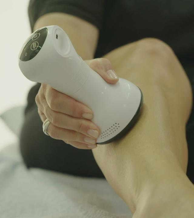Lymphdrainage-Massage-Gerät wird über Bein gefahren