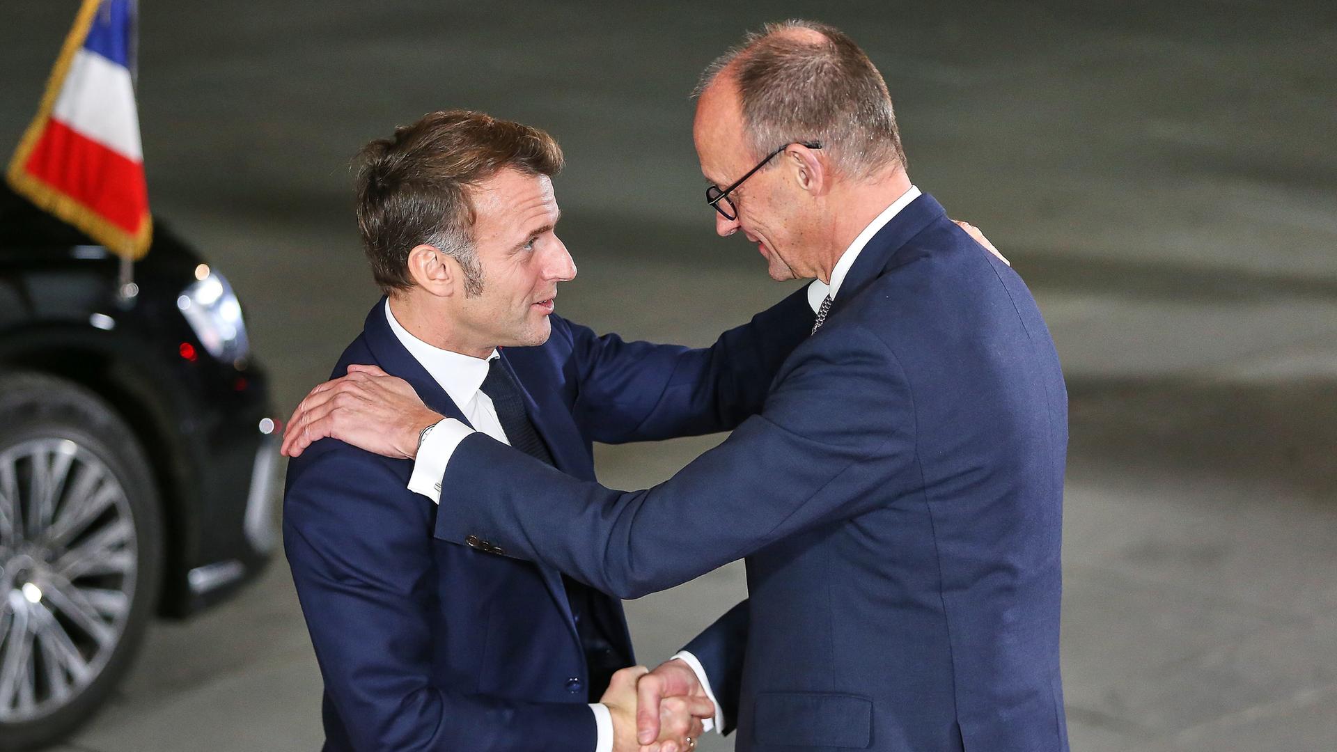 Emmanuel Macron und Friedrich Merz schütteln sich die Hände.