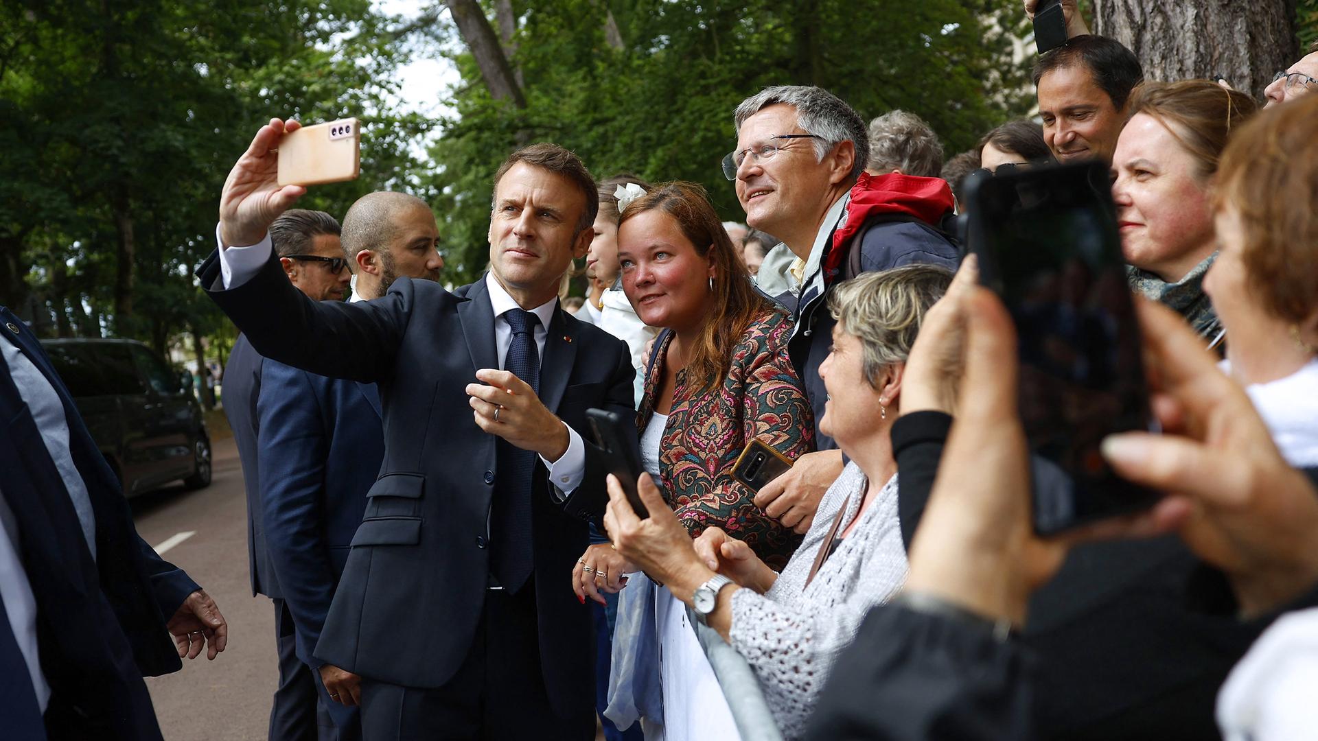Frankreichs Präsident Emmanuel Macron macht ein Selfie mit Wählern.