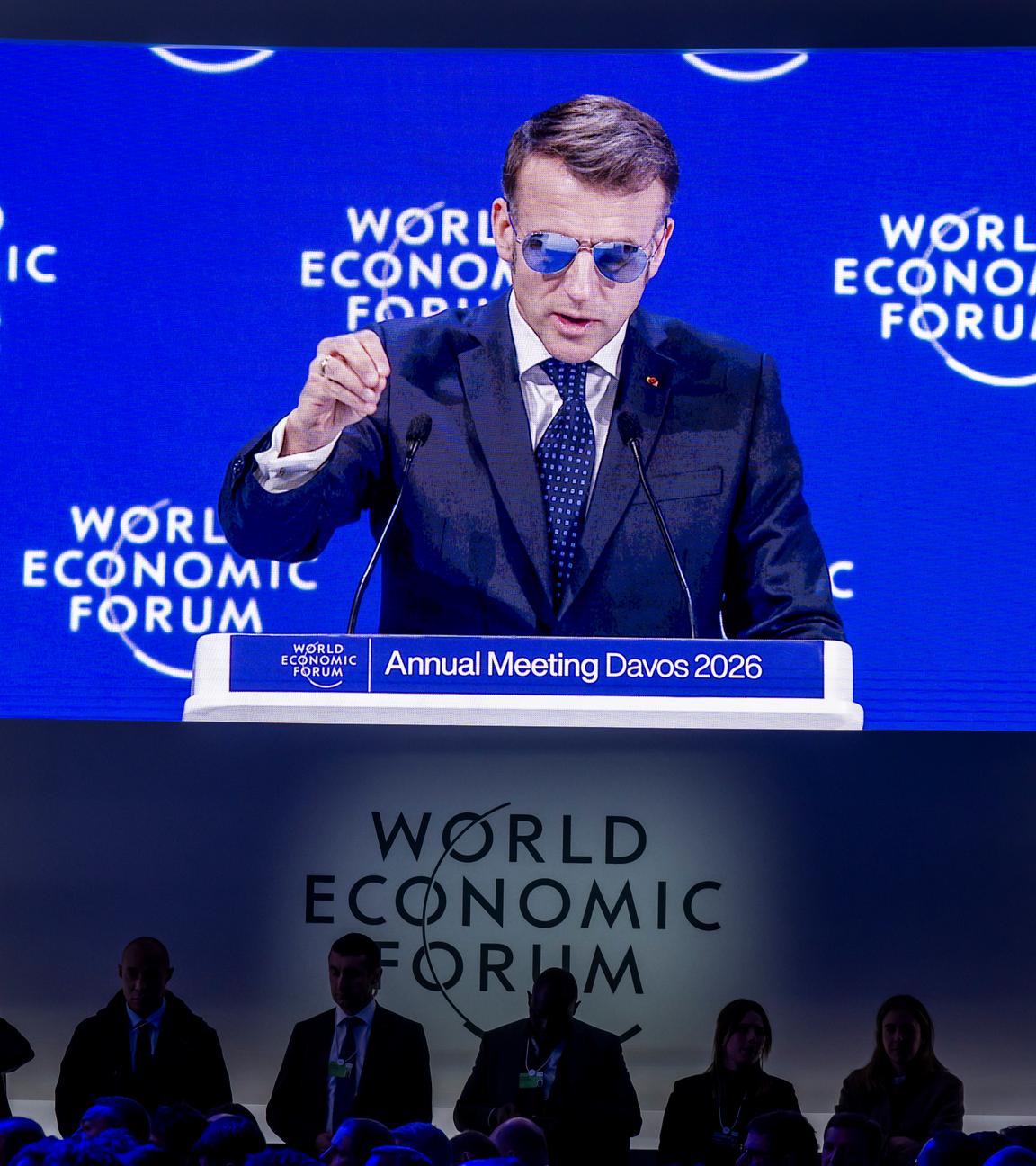Schweiz, Davos: Frankreichs Präsident Macron trägt eine Sonnenbrille und ist auf einem großen Bildschirm zu sehen.