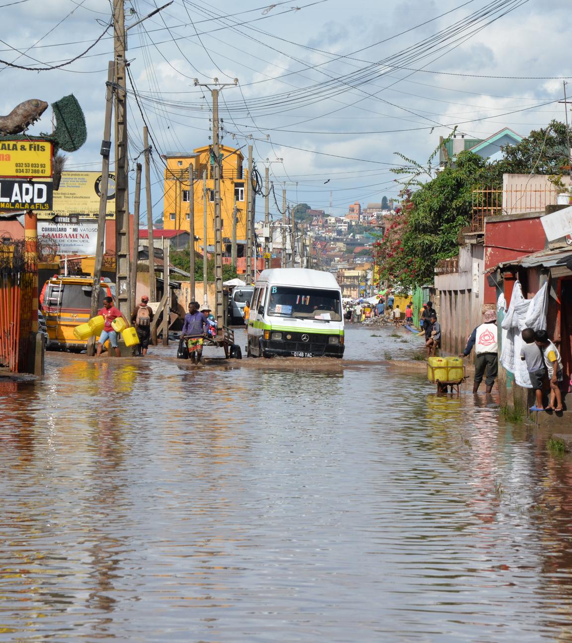 2.02.2026, Madagaskar, Antananarivo: Menschen und Autos bahnen sich einen Weg durch eine überflutete Straße.