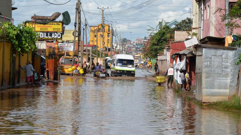 2.02.2026, Madagaskar, Antananarivo: Menschen und Autos bahnen sich einen Weg durch eine überflutete Straße.