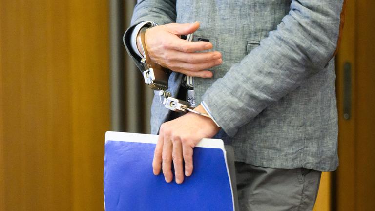 Der im Fall "Maddie" Verdächtige Christian B. kommt in Handschellen und mit einem Aktenordner in der Hand in den Gerichtssaal im Landgericht Braunschweig. (Achiv)