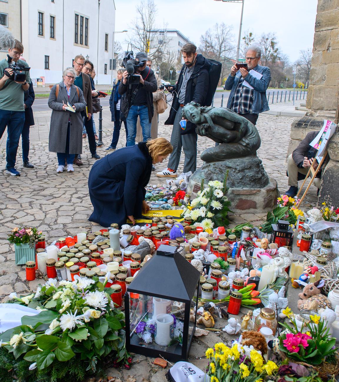 Am Gedenkort des Anschlags am Magdeburger Weihnachtsmarkt legt eine Frau Blumen ab, umringt von trauernden Menschen.