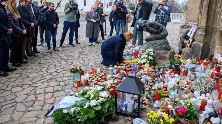 Am Gedenkort des Anschlags am Magdeburger Weihnachtsmarkt legt eine Frau Blumen ab, umringt von trauernden Menschen.