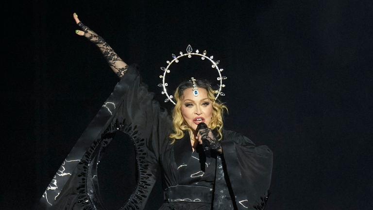 Madonna - ganz in schwarz - hält ihr Mikro während des Auftritts in der Hand.