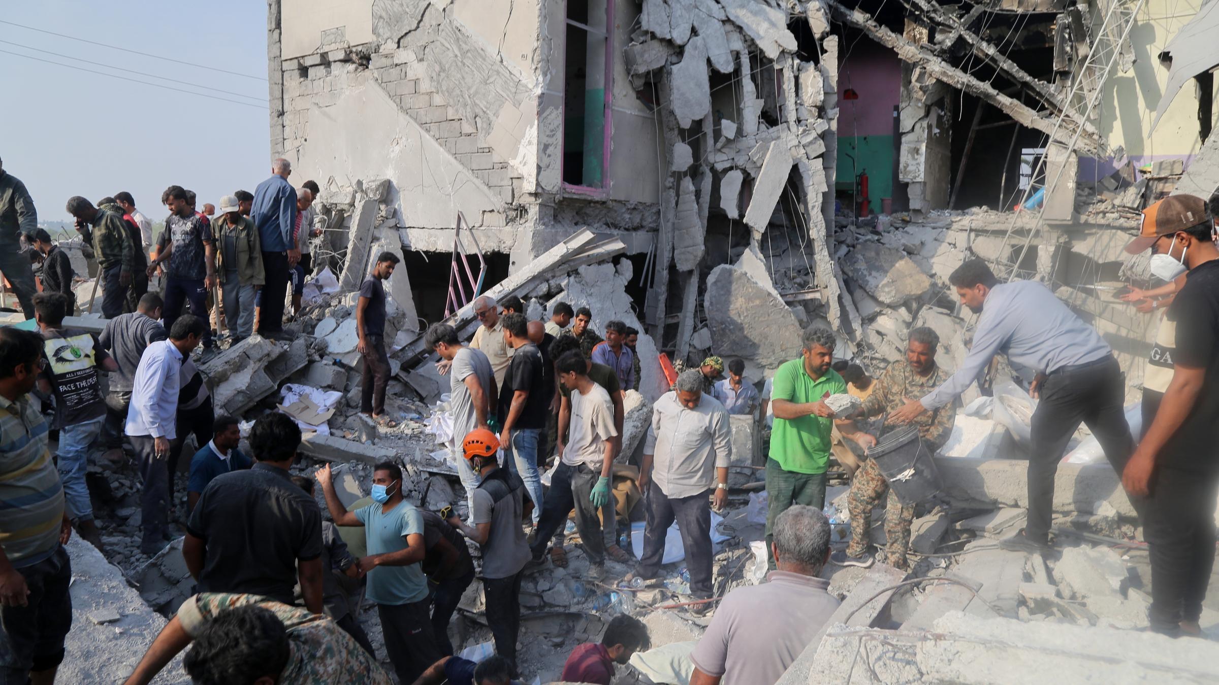 Rettungskräfte und Anwohner durchsuchen am 28.2.2026 die Trümmer nach einem Angriff auf eine Grundschule für Mädchen.