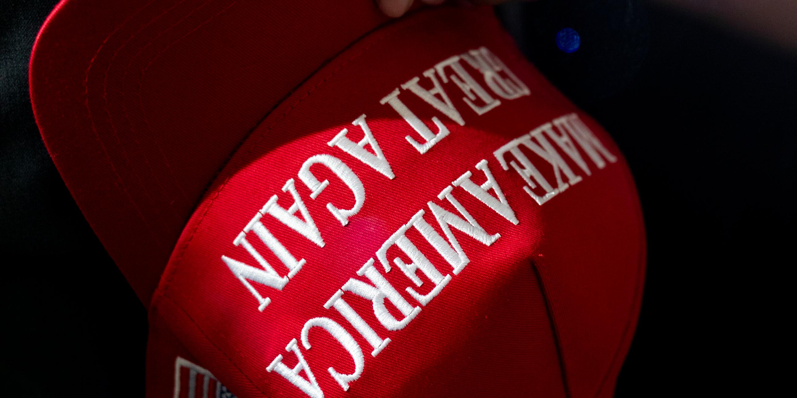 Eine Person hält eine rote MAGA-Kappe ("Make America Great Again“), während sie auf eine Rede von Donald Trump am Macomb Community College wartet.