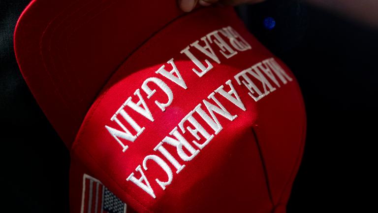 Eine Person hält eine rote MAGA-Kappe ("Make America Great Again“), während sie auf eine Rede von Donald Trump am Macomb Community College wartet.