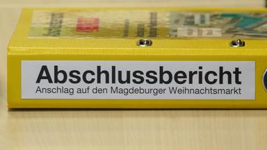 Ein Aktenordner mit der Aufschrift "Abschlussbericht - Anschlag auf den Magdeburger Weihnachtsmarkt" liegt bei einer Pressekonferenz