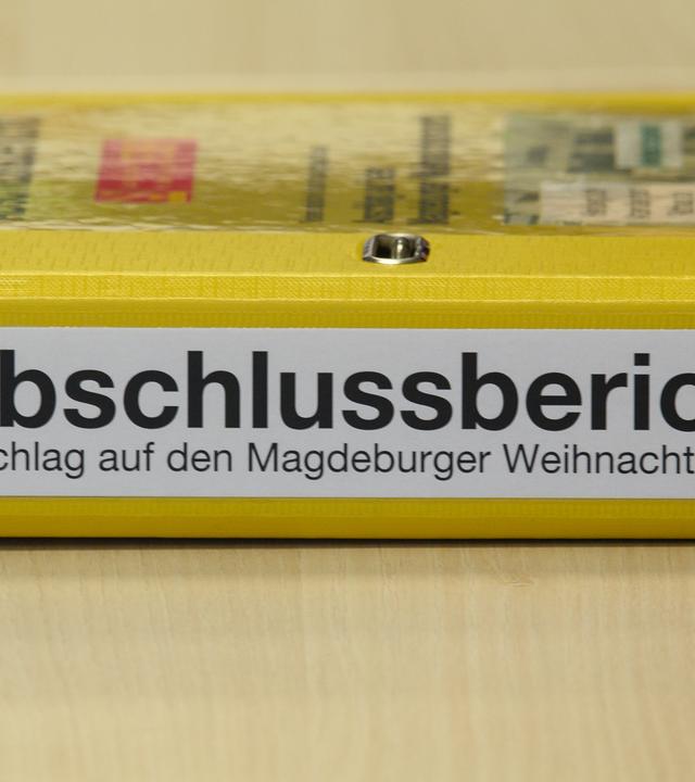 Ein Aktenordner mit der Aufschrift "Abschlussbericht - Anschlag auf den Magdeburger Weihnachtsmarkt" liegt bei einer Pressekonferenz