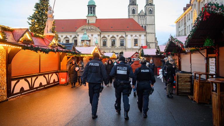 Drei Polizisten gehen über den Magdeburger Weihnachtsmarkt