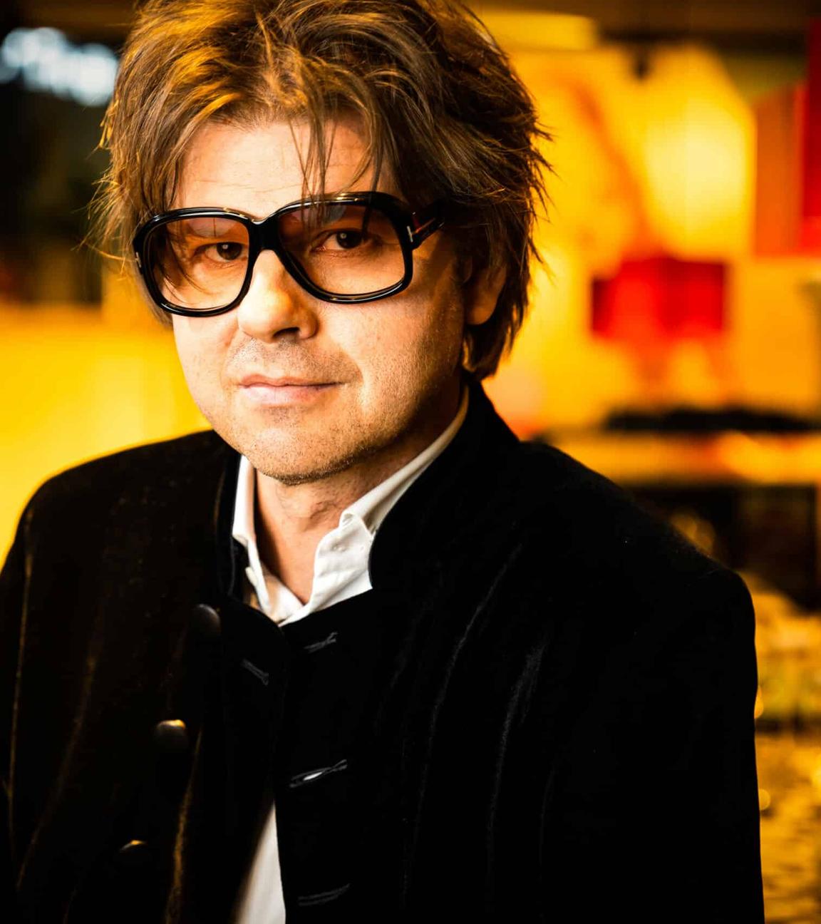 Magnus Lindgren, halbtotal mit "Straight-out-of-bed"-Frisur und einer übergroßen Brille, gelassen in die Kamera schauend.