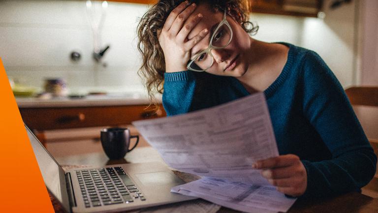 Frau sitzt am Tisch und schaut auf ihre Rechnung