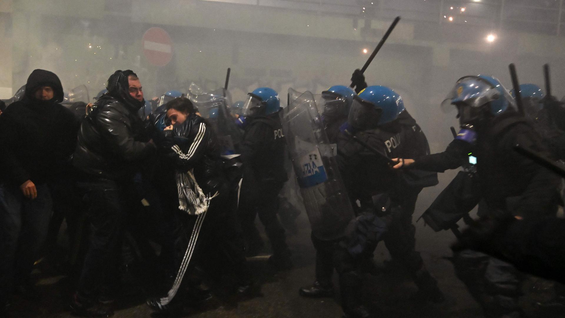 Polizisten gehen mit Schlagstöcken gegen Demonstranten vor.