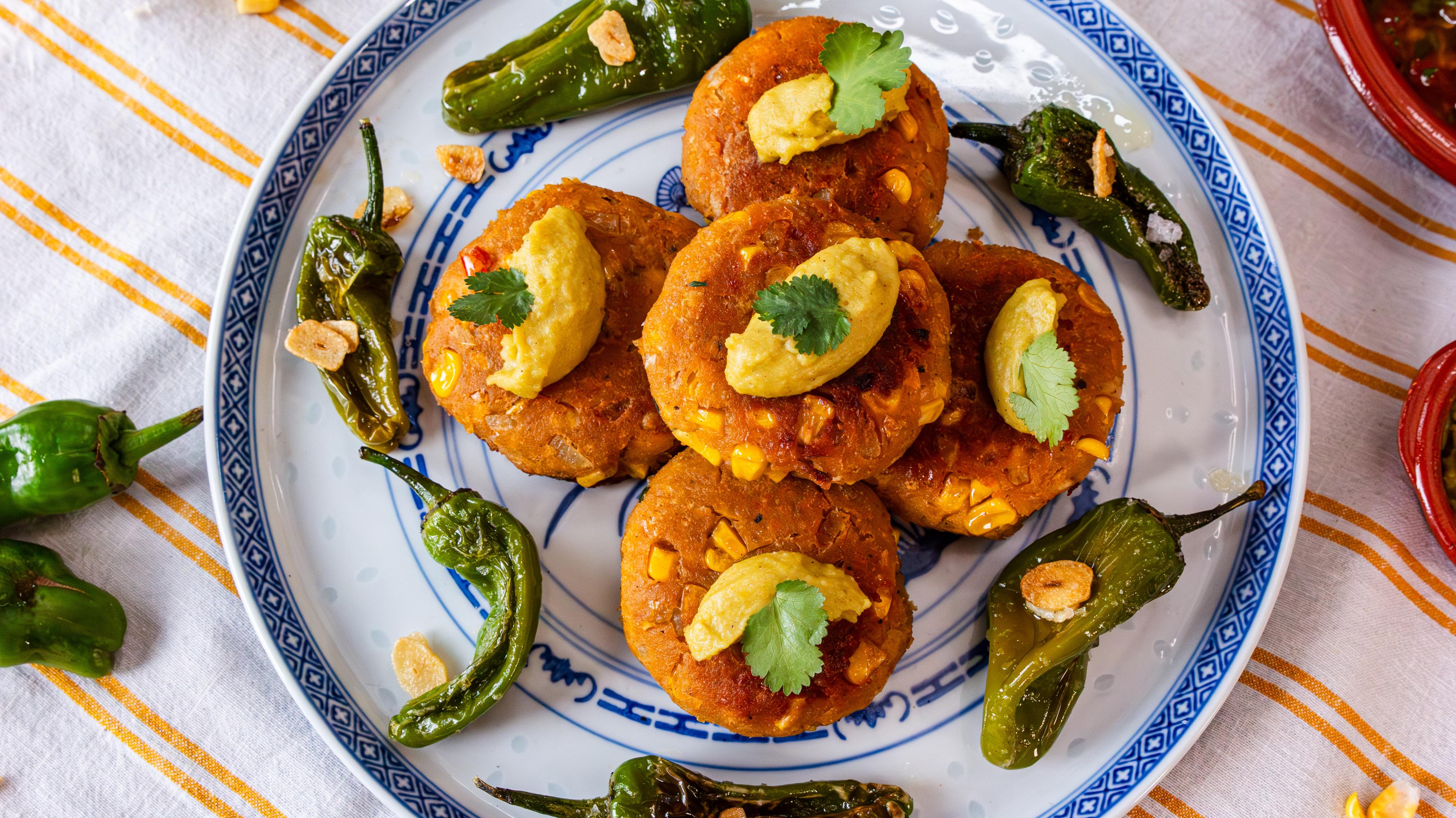 Frikadellen aus Mais, getoppt mit Wasabi-Hummus und Bratpaprika an der Seite