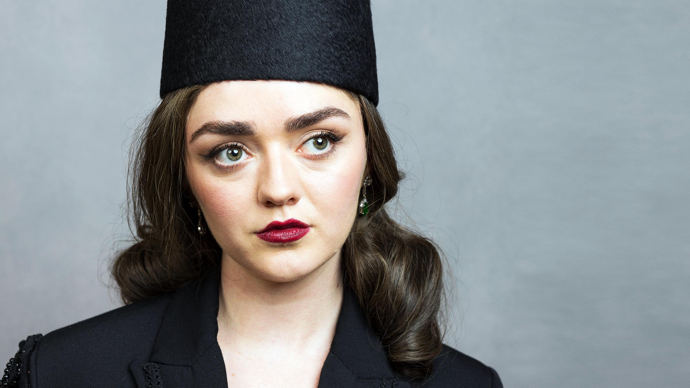 Maisie Williams mit Hut und roten Lippenstift in einer nahen Einstellung