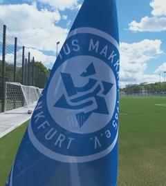 Die Makkabi-Fahne ist im Vordergrund zu sehen, ein Fußballfeld ist im Hintergrund.