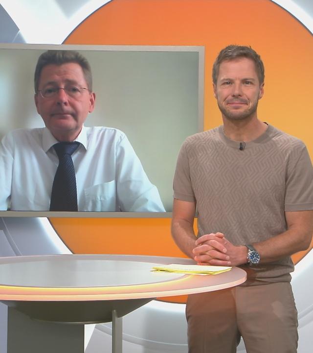 Florian Weiss im VK-Studio mit Prof. Tomas Jelinke im Hintergrund auf dem Bildschirm