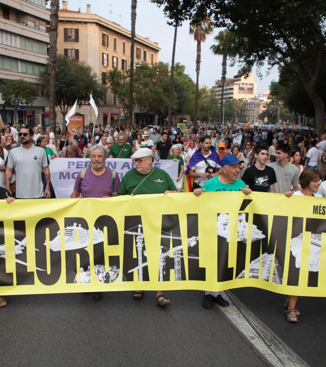 Spanien, Palma: Teilnehmer des Protestzugs in Palma halten ein Banner mit der Aufschrift "Mallorca al limit!" während einer Demonstration gegen den Massentourismus auf Mallorca