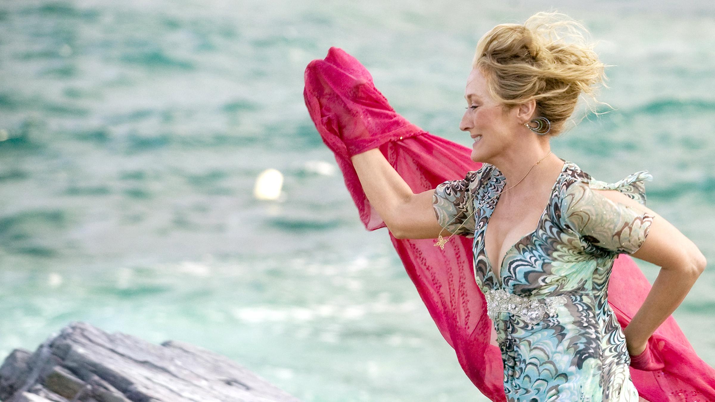 Donna (Meryl Streep) läuft in einem leichten Sommerkleid und mit wehendem Tuch am Strand entlang.