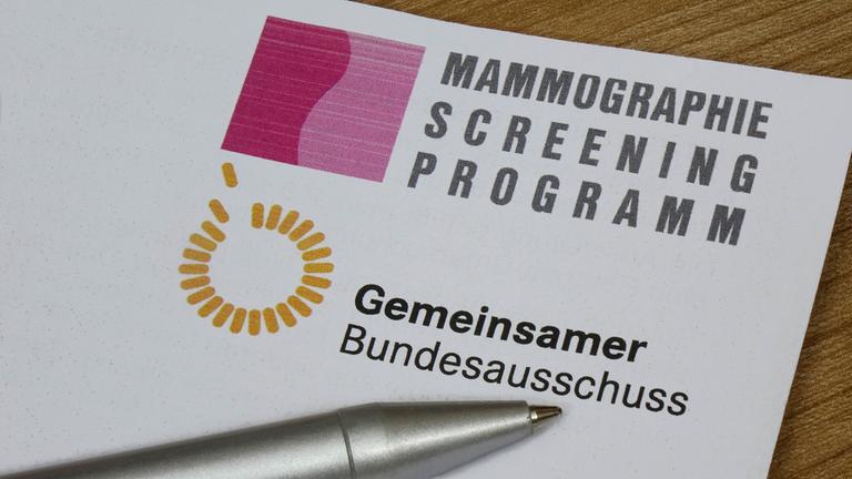 Auf einer Broschüre zum Mammographie-Screening-Programm befindet sich ein Kugelschreiber.