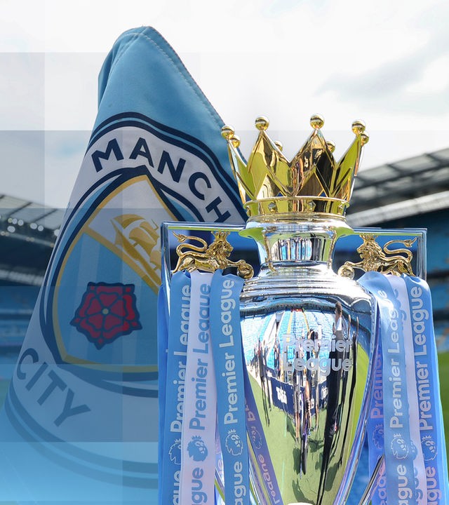 Die Eckfahne im Fußballstadion von Manchester City, welche das Logo zeigt. Daneben ist die Trophäe für das Gewinnen der Premier League abgebildet.