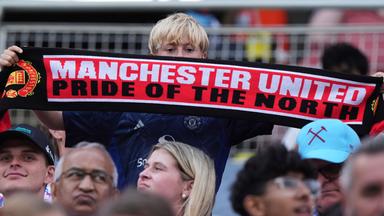 Ein Manchester United Fan hält einen Schal mit der Aufschrift: "Manchester United, Pride of the North" hoch.