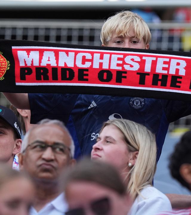Ein Manchester United Fan hält einen Schal mit der Aufschrift: "Manchester United, Pride of the North" hoch.