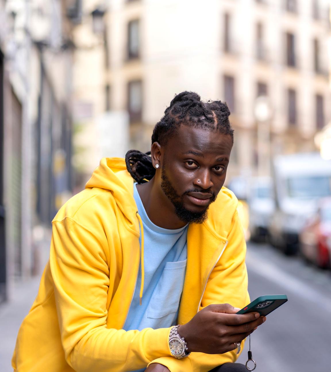 Junger Mann mit Afrohaaren lässt sich von Smartphone durch Stadt navigieren