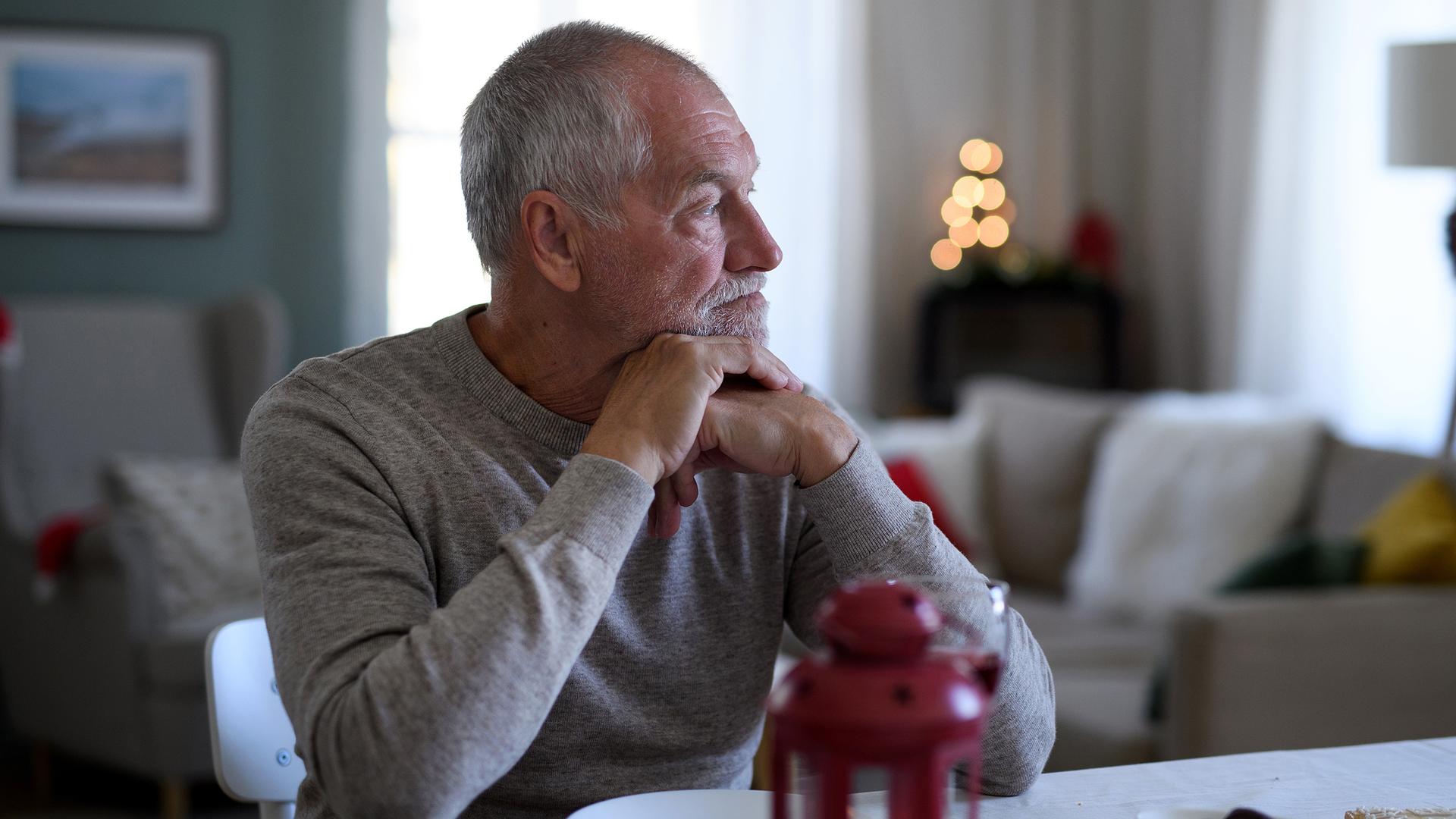 Älterer Mann sitzt alleine am Esstisch