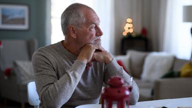 Älterer Mann sitzt alleine am Esstisch