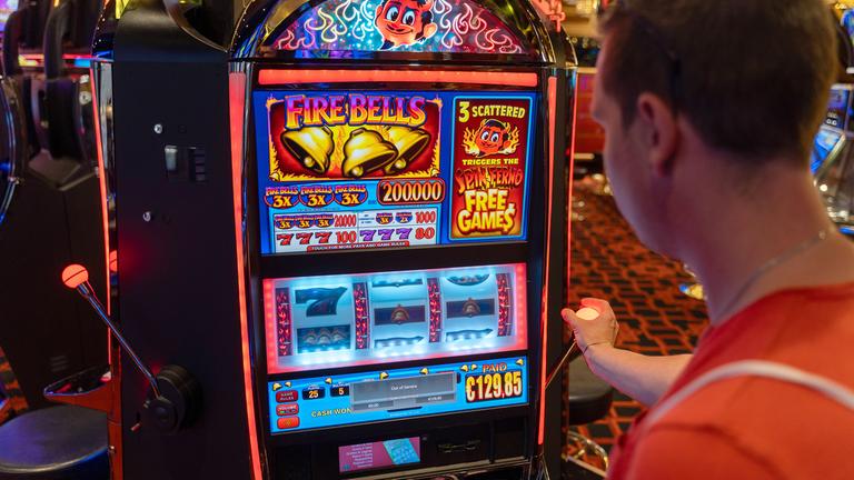 Ein junger Mann spielt an einem Spielautomaten in einem Casino