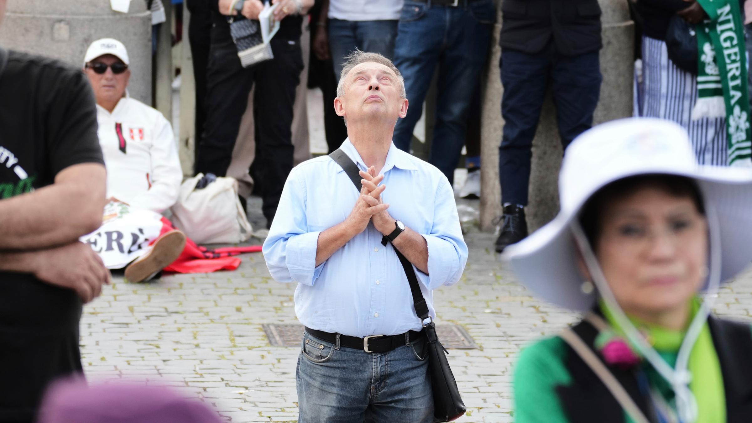 Ein Mann kniet und betet, als Papst Leo XIV. auf dem Petersplatz im Vatikan eine Messe zur feierlichen Eröffnung seines Pontifikats zelebriert.